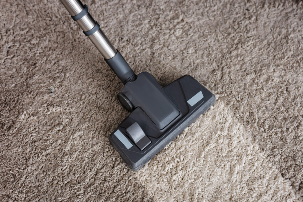 Top view of brush of vacuum cleaner on dirty carpet at home